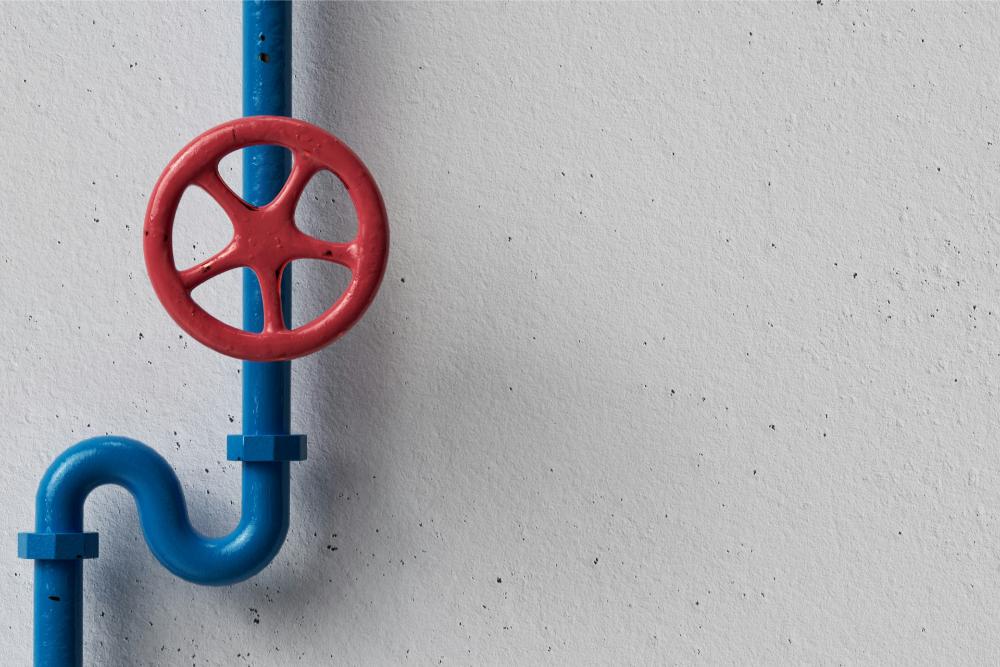 Red valve on blue pipe, white wall