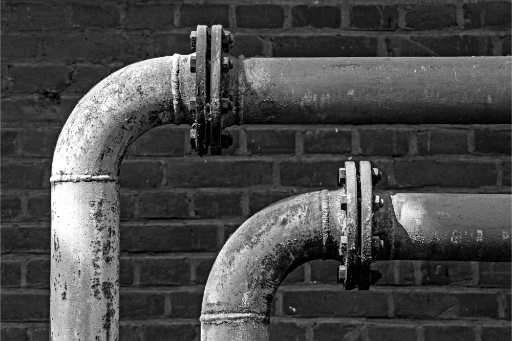 Two pipes with flanges on brick wall