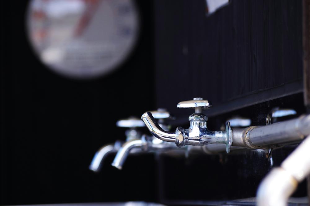 close-up of a faucet with a clock in the background